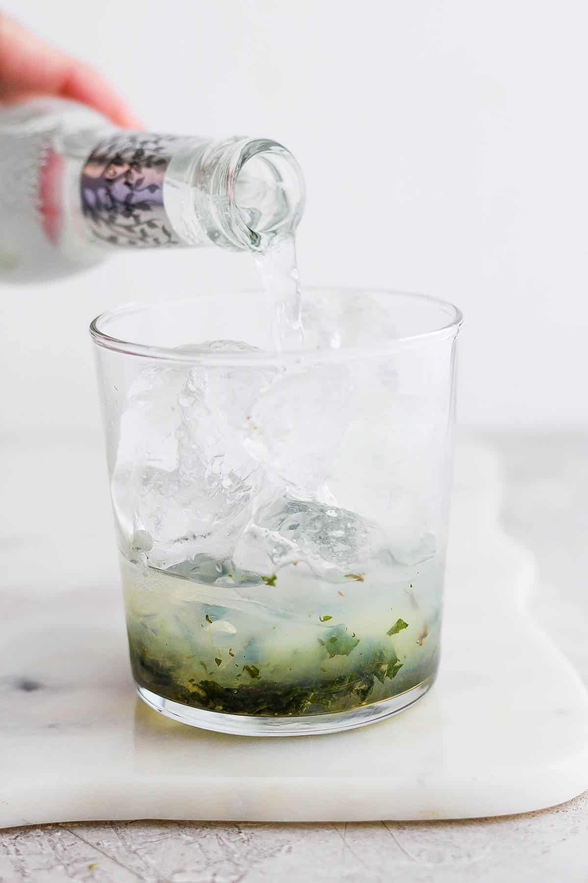 Tonic water being added to the mojito.