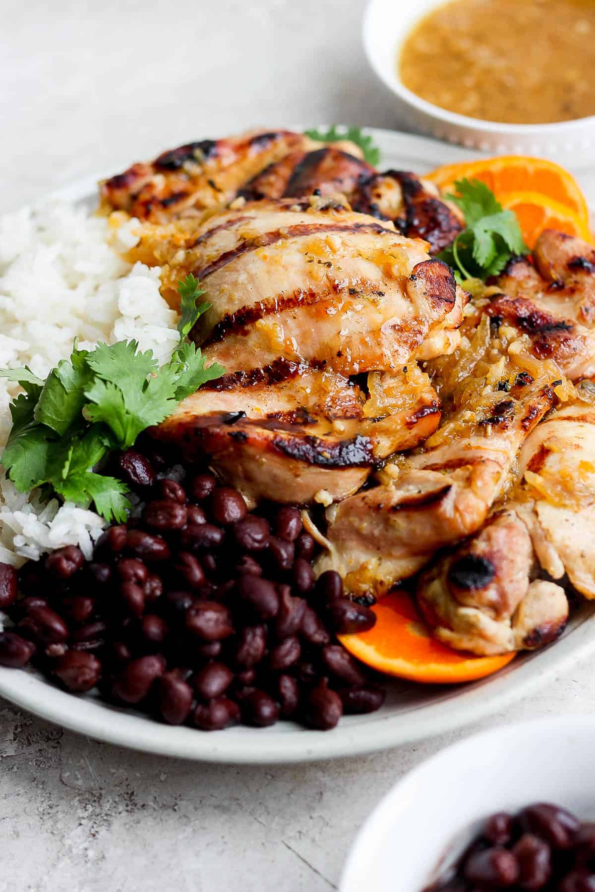 Mojo chicken on a white plate with rice and black beans.