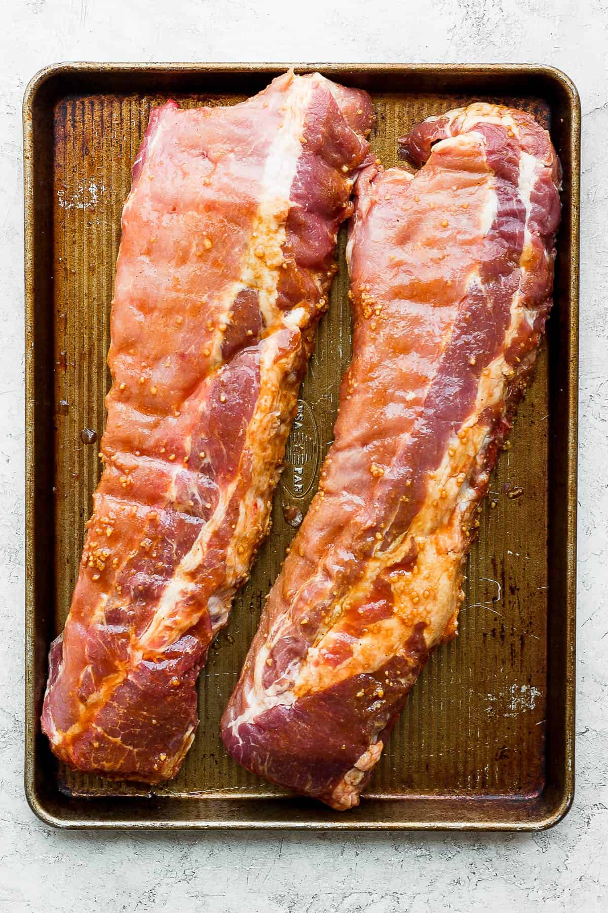 Marinated ribs on a baking sheet.