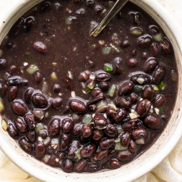 Bowl of seasoned black beans with a spoon sticking out.