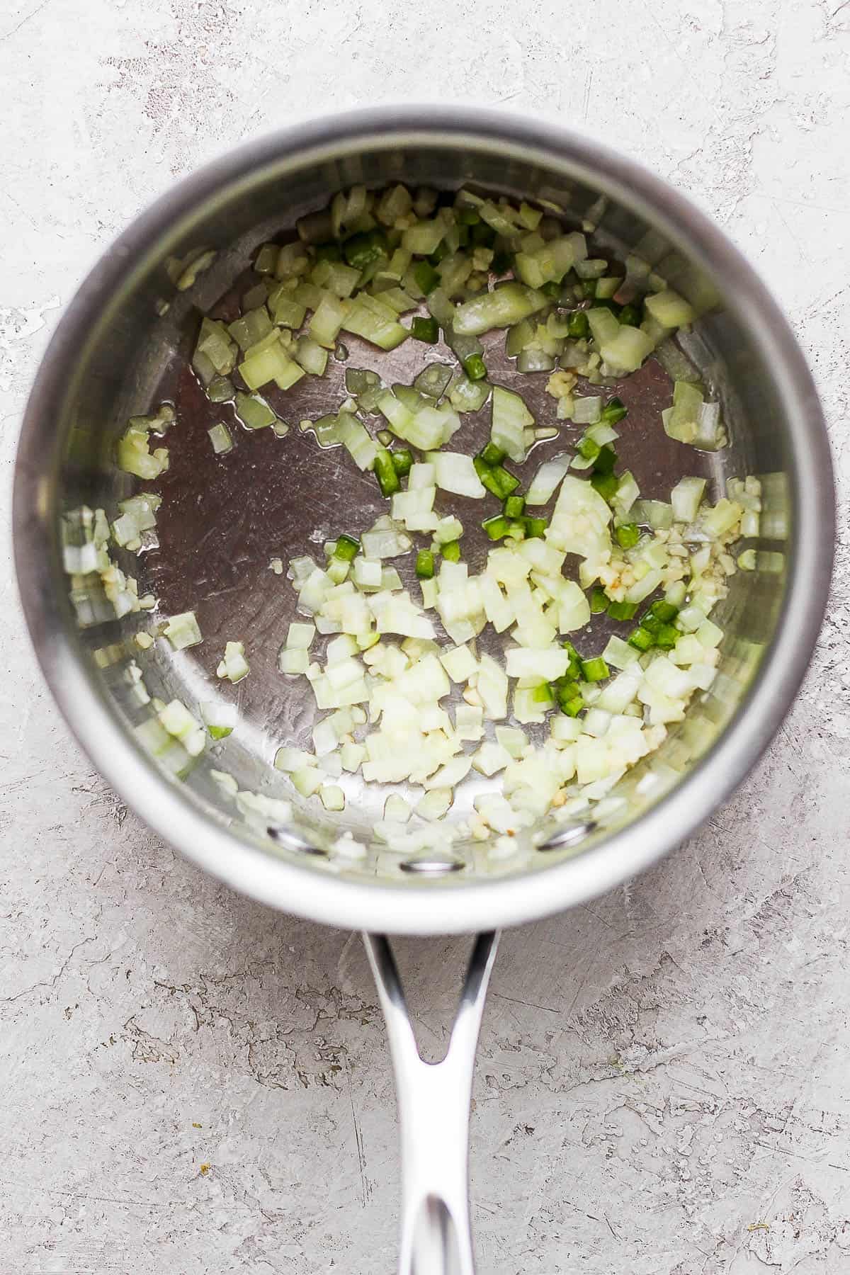 garlic, onion, and jalapeno sauteing in a pan.