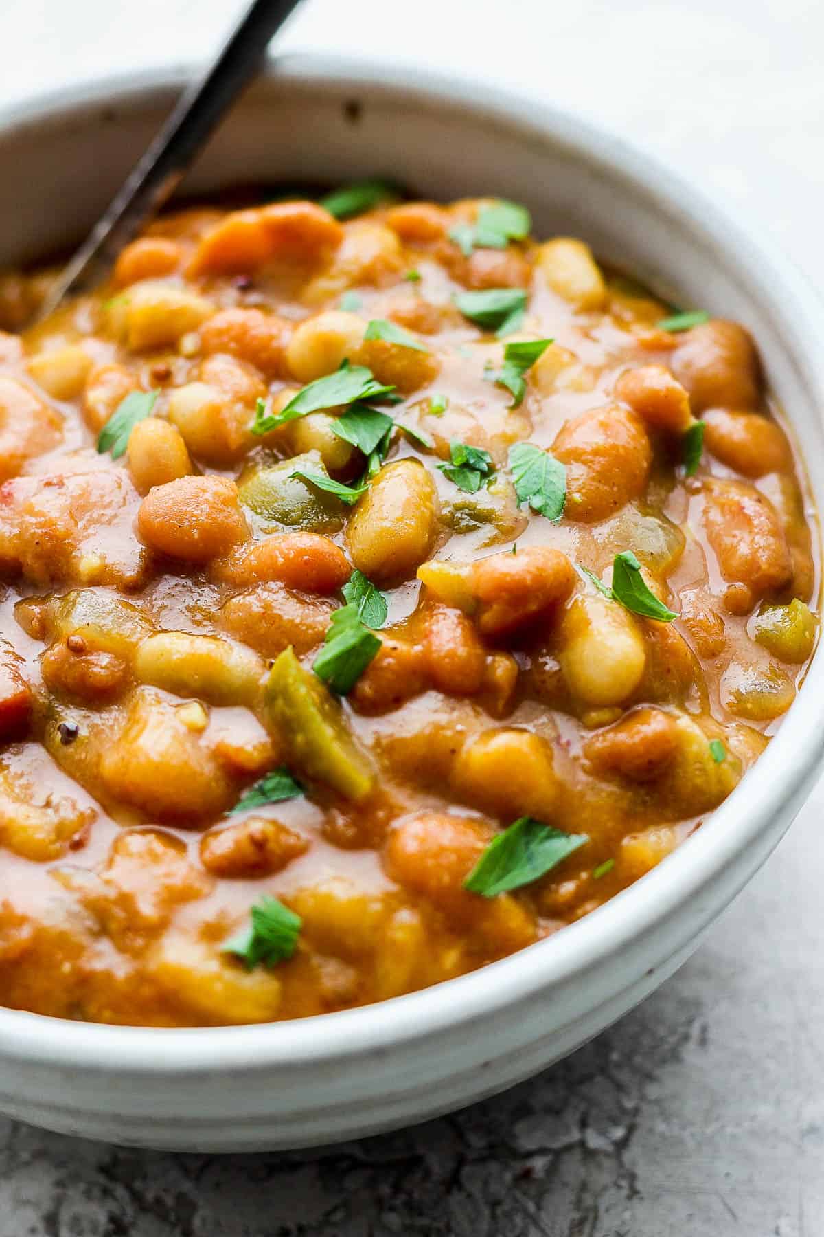 Slow cooker baked beans in a bowl with a spoon.