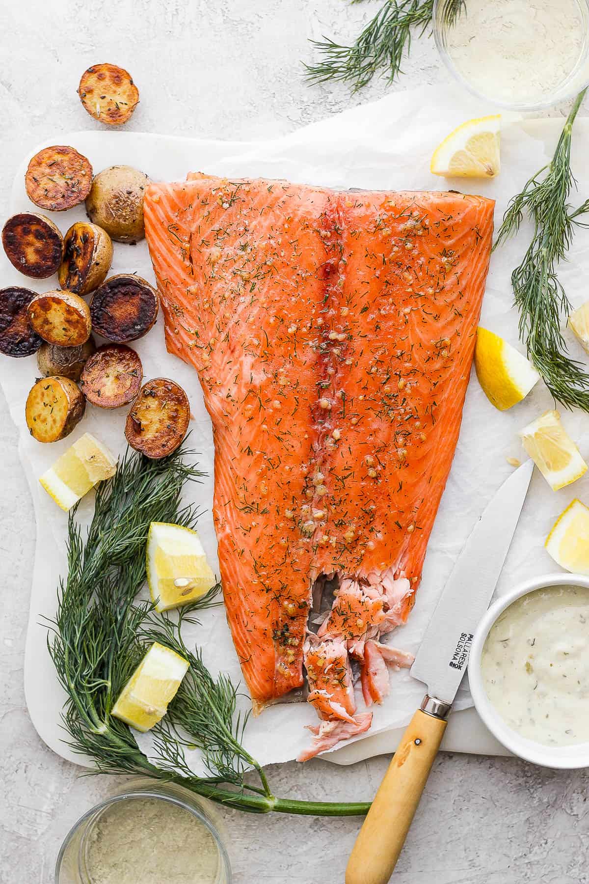 A smoked salmon fillet on parchment paper with a side of roasted potatoes.