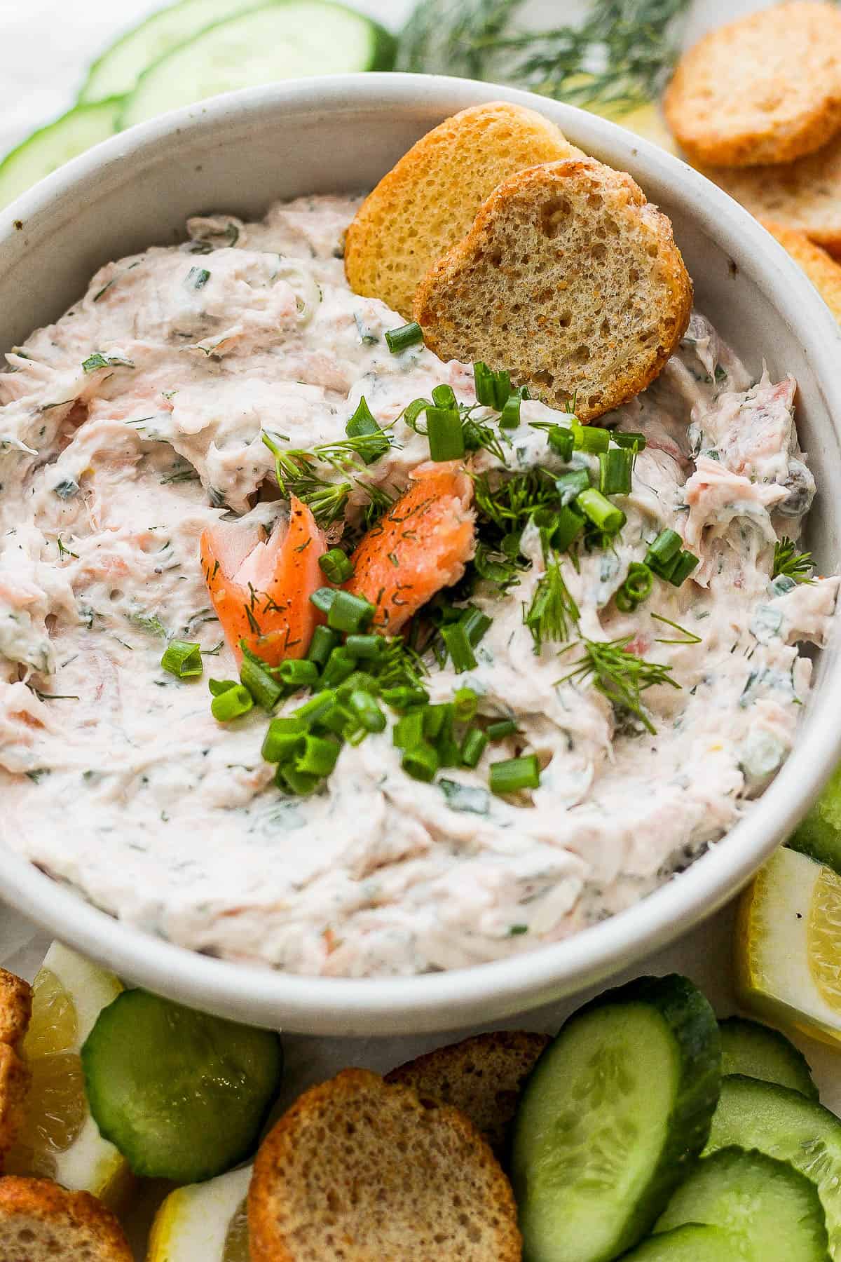 Two crostini crackers sticking out of a bowl of smoked salmon dip.