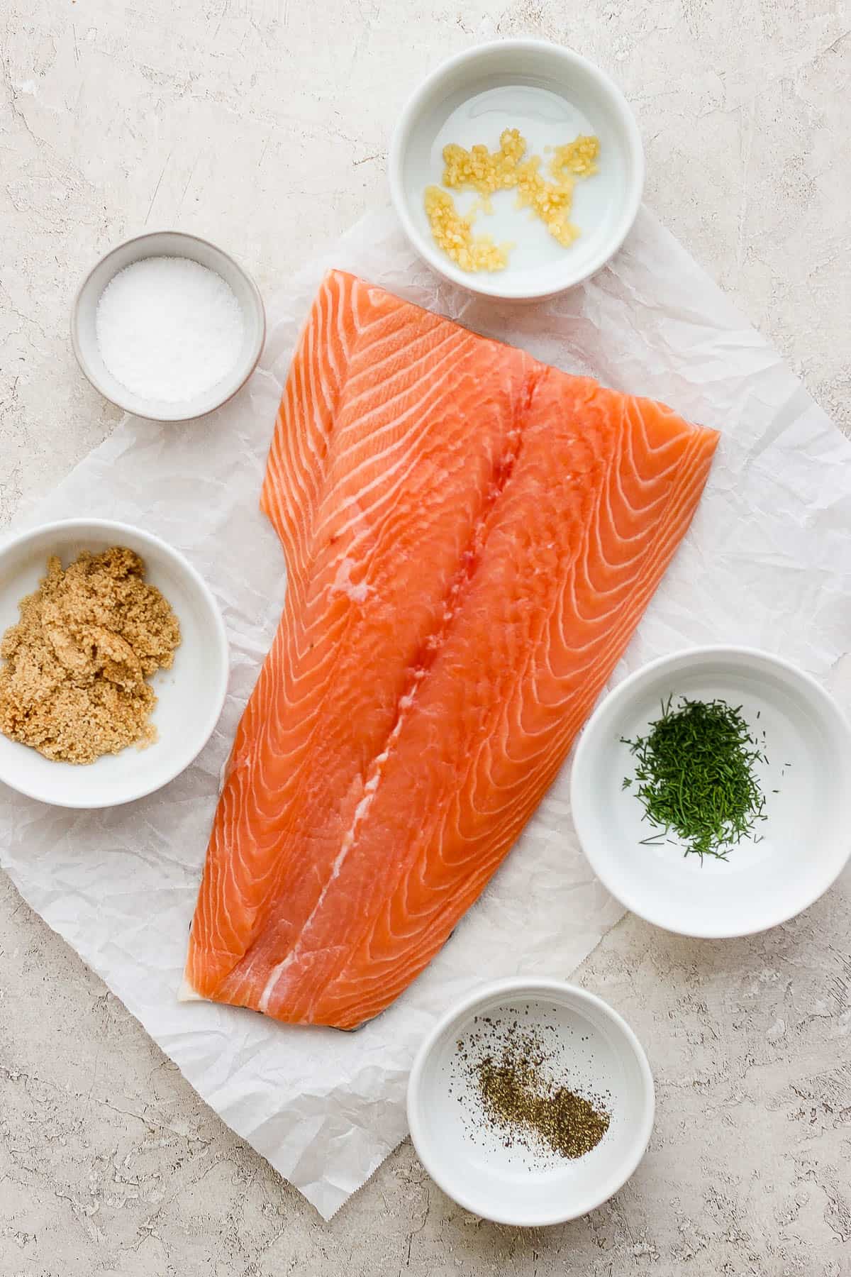 The ingredients for smoked salmon in separate dishes.