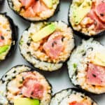 A plate of spicy tuna rolls cut into slices with avocado.