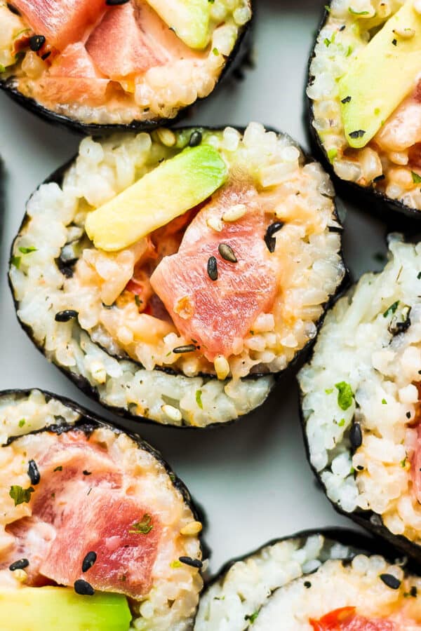 A plate of spicy tuna rolls cut into slices with avocado.