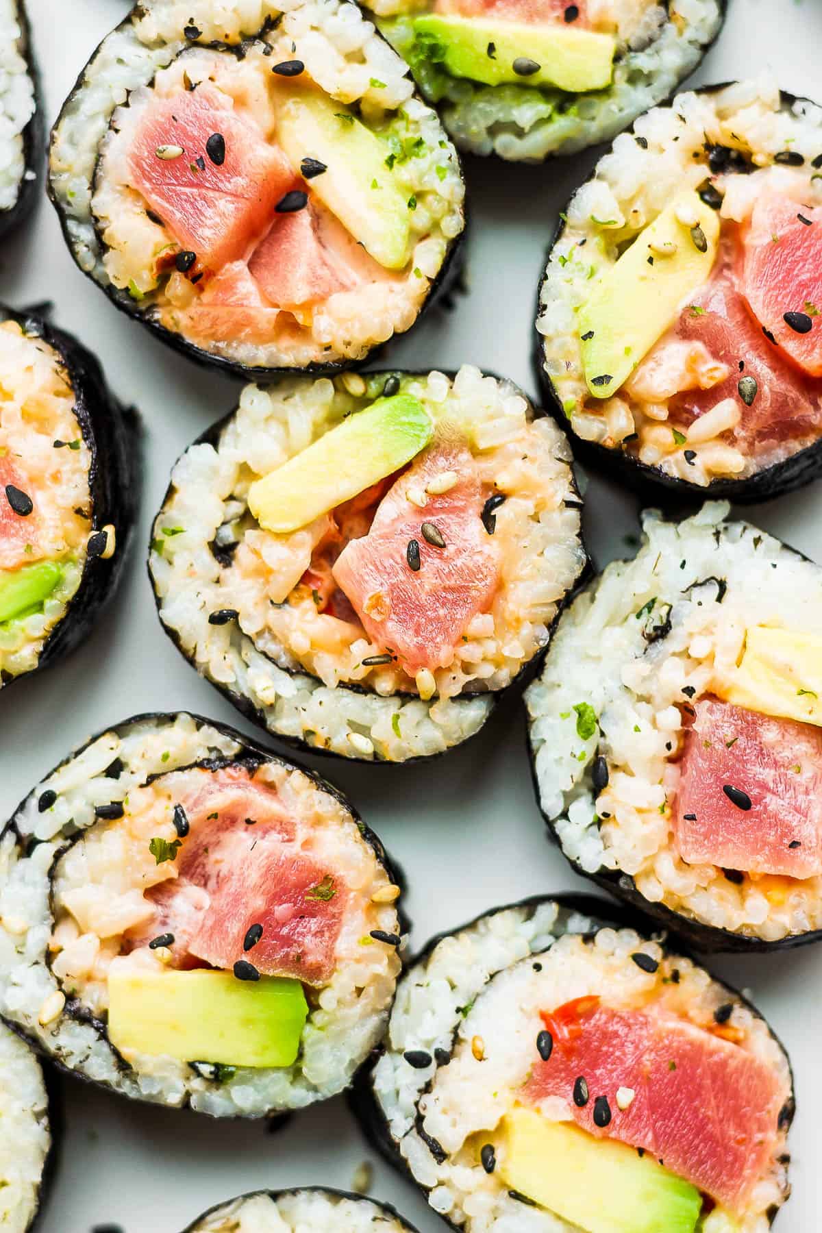 Pieces of a spicy tuna roll on a white plate.