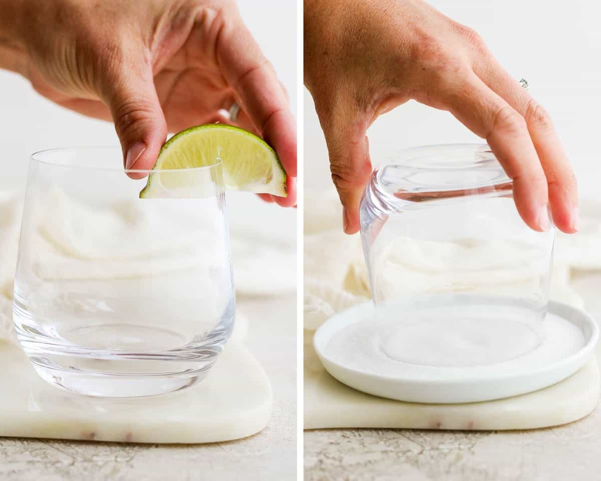 A hand pressing a lime wedge on the rim of a class.  A hand twisting the glass rim into a plate of sugar.