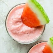 Top down shot of two glasses of watermelon smoothie with small wedges of watermelon sticking out.