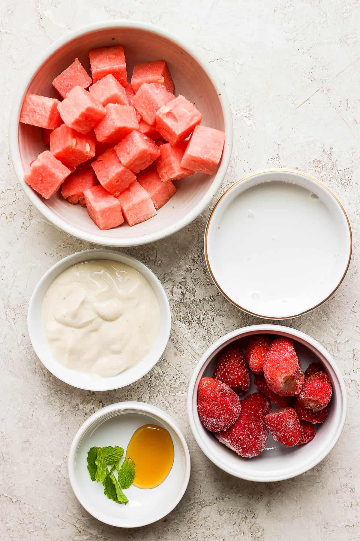 Ingredients for a watermelon smoothie in separate bowls.