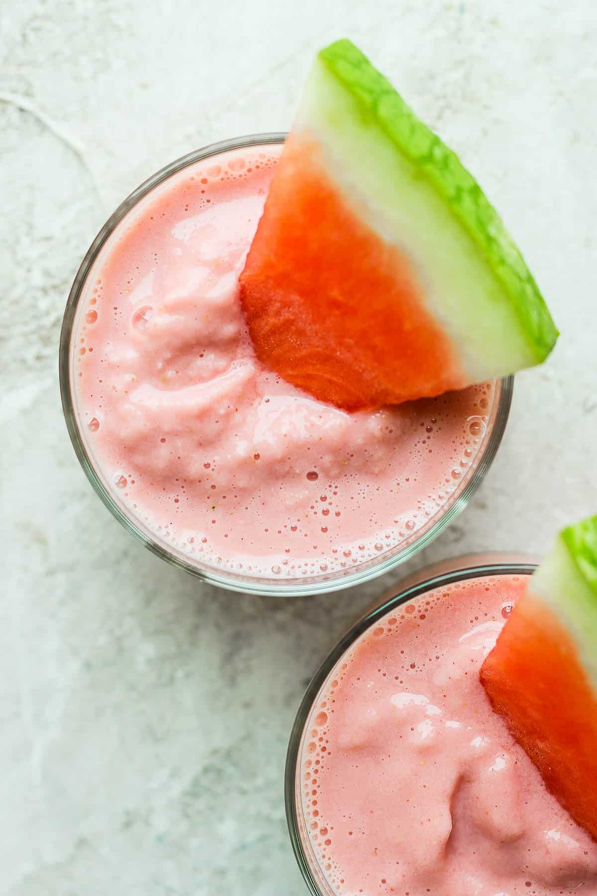 Watermelon smoothies in glasses with a slice of fresh watermelon in the top.