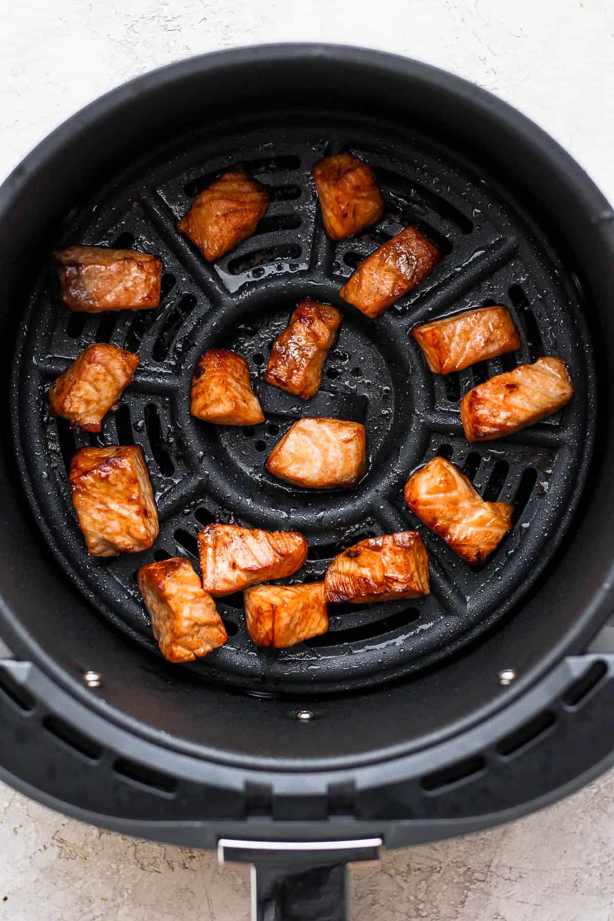 Salmon bites in the air fryer basket after cooking.