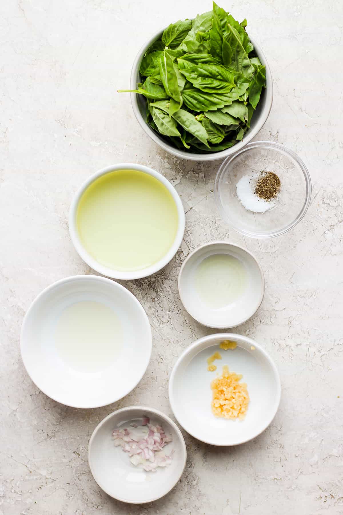 Ingredients for a basil vinaigrette in separate bowls.