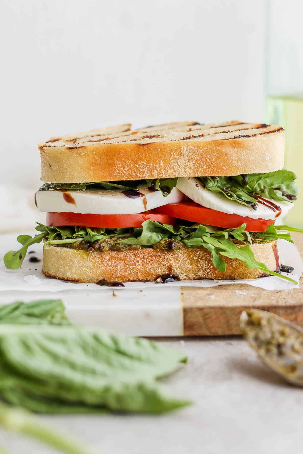 A complete caprese sandwich on a piece of parchment paper.