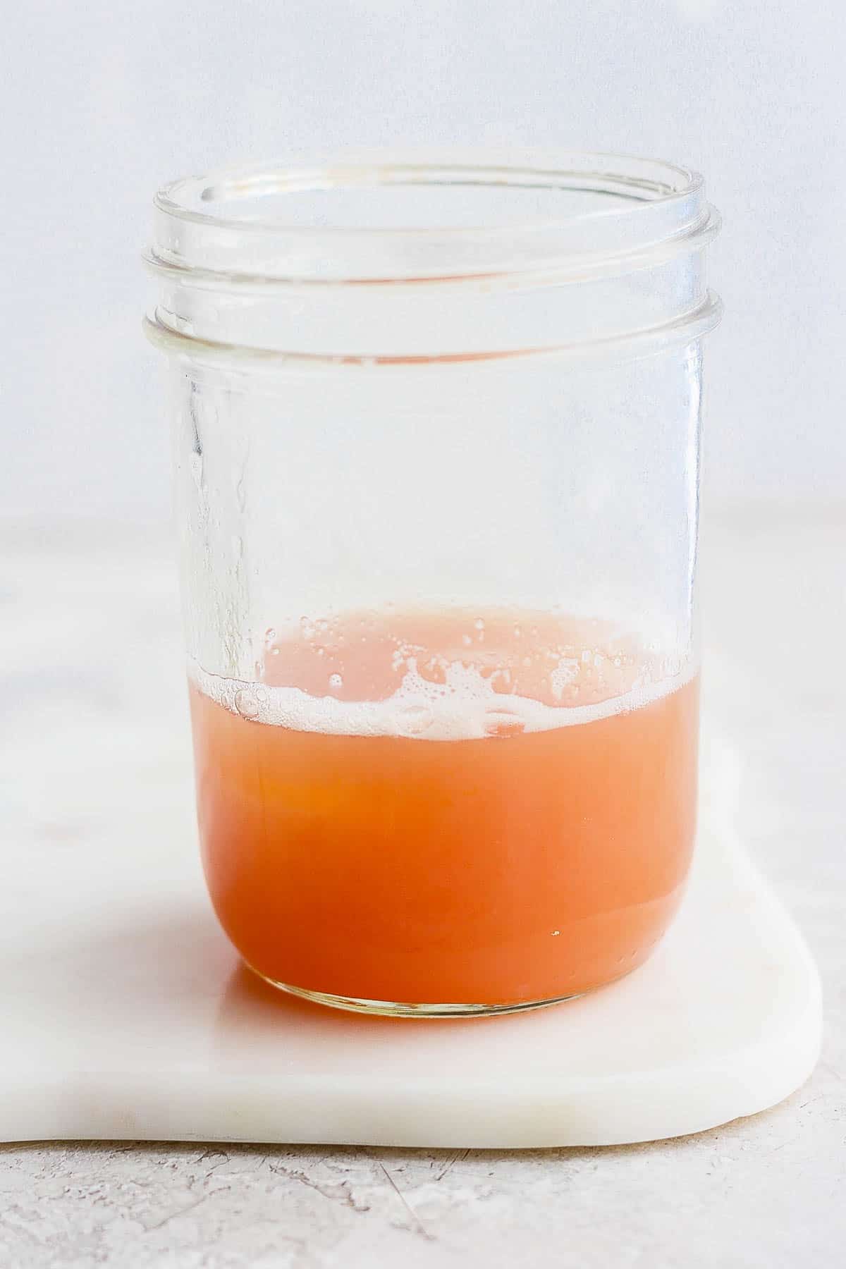 Ingredients for a cranberry orange whiskey sour in a mason jar.