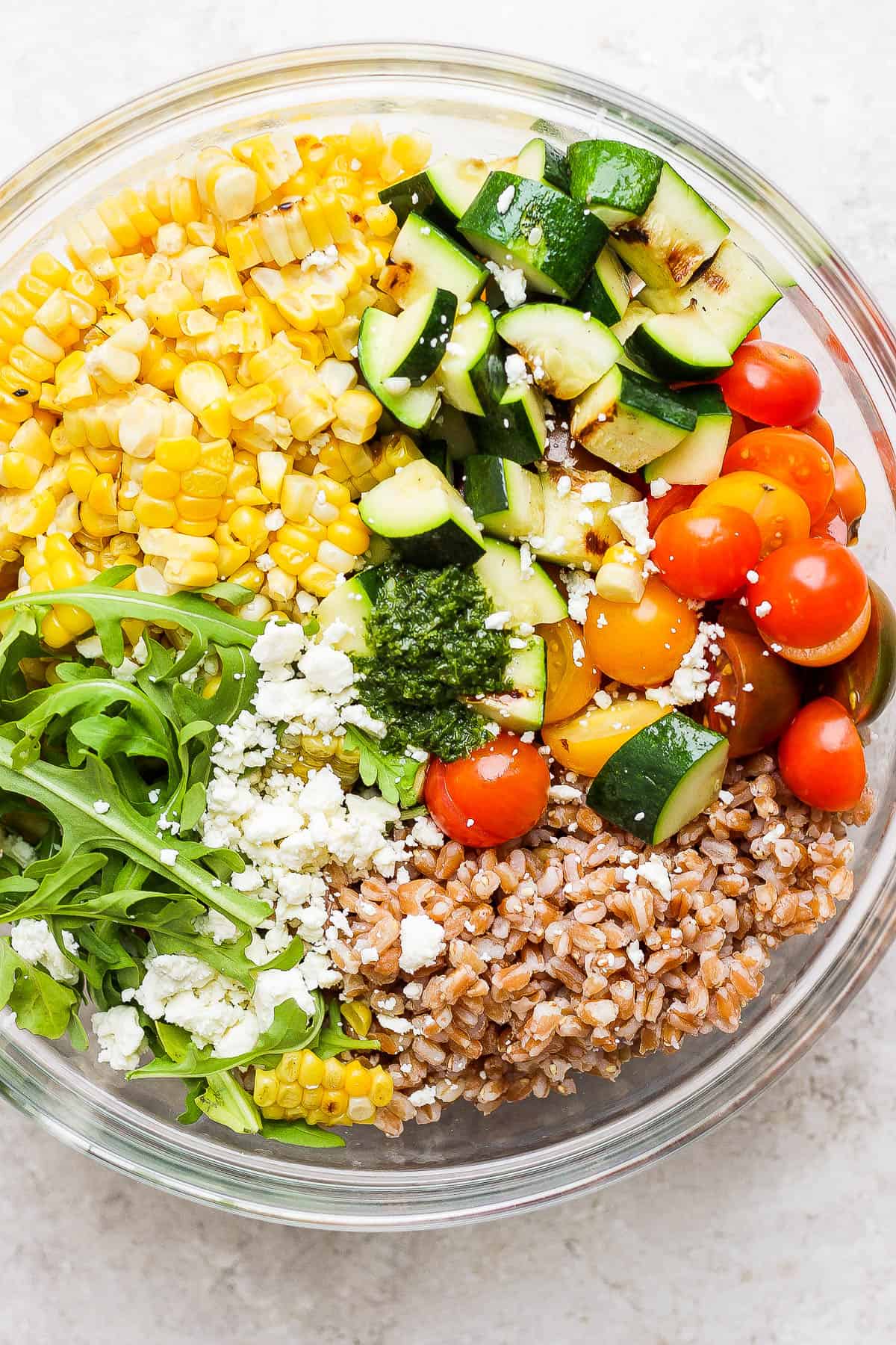 The grain salad in a large glass bowl before the vinaigrette is added.