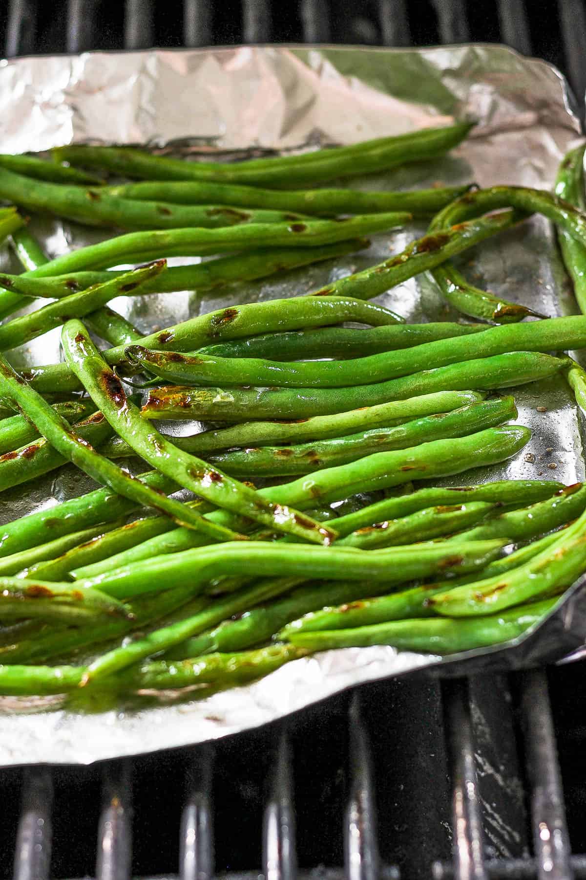 Green beans on a aluminum foil tray on the grill.