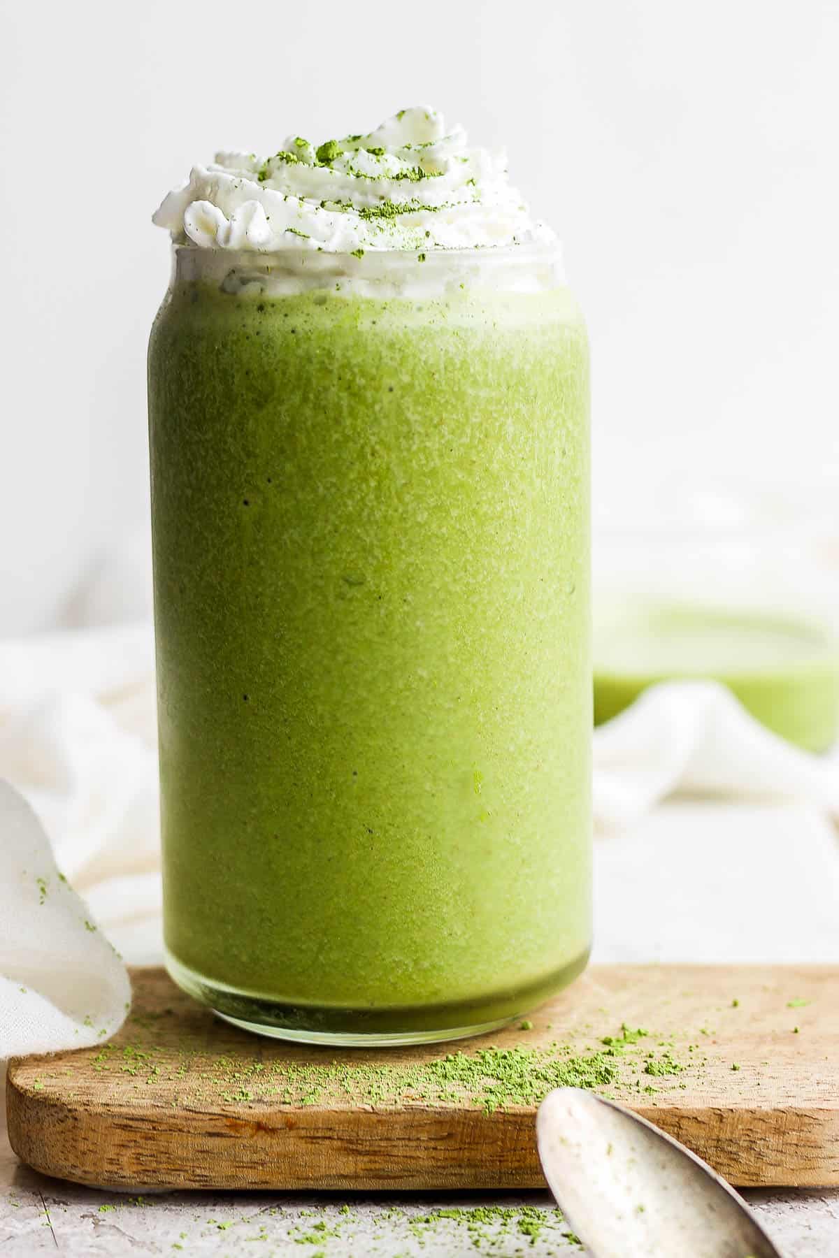 A matcha smoothie with whipped cream on top.