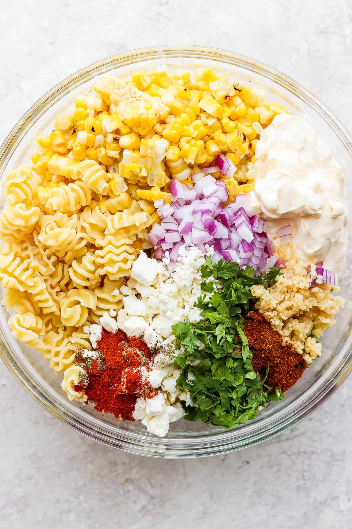 All of the pasta salad ingredients in a medium sized mixing bowl.