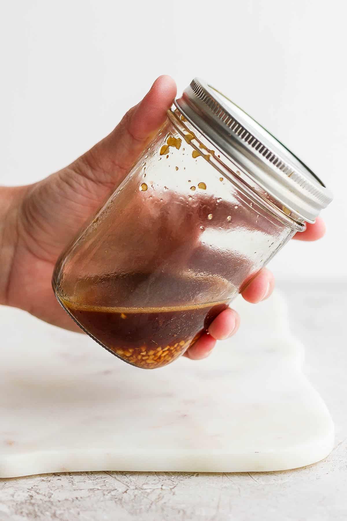 Sesame ginger dressing in a mason jar being held by a hand.
