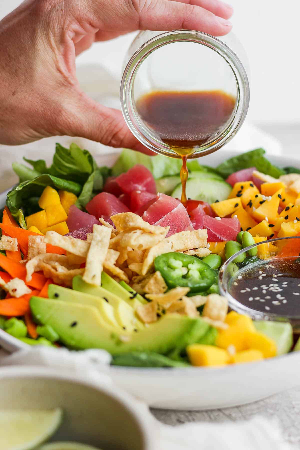 Sesame ginger dressing being poured over a poke salad.