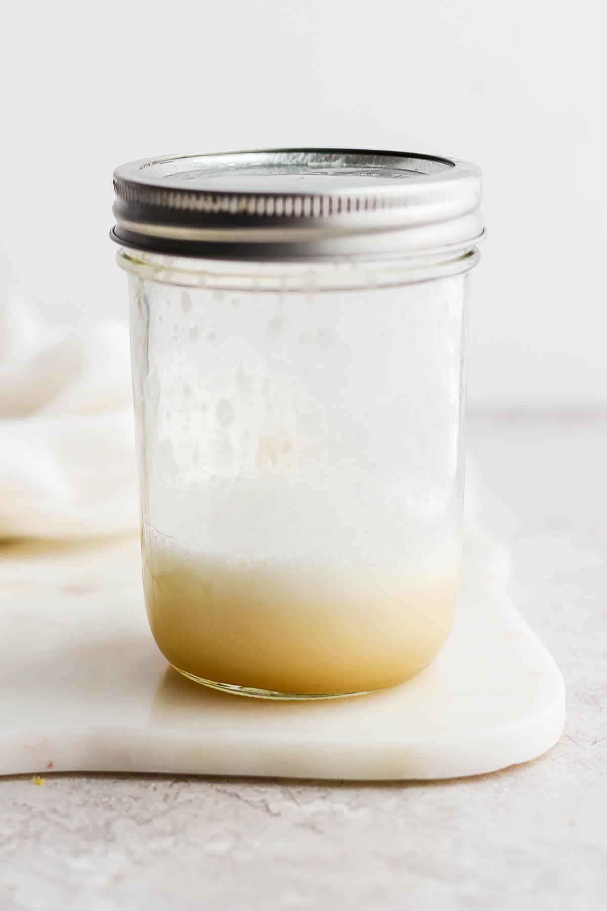 A shaken whiskey sour in a mason jar with the lid on top.