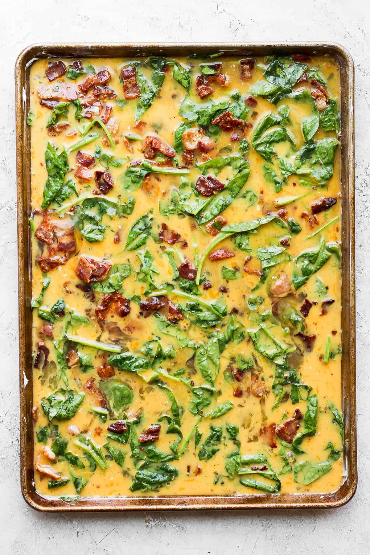 The egg and bacon mixture poured into the prepared baking sheet.