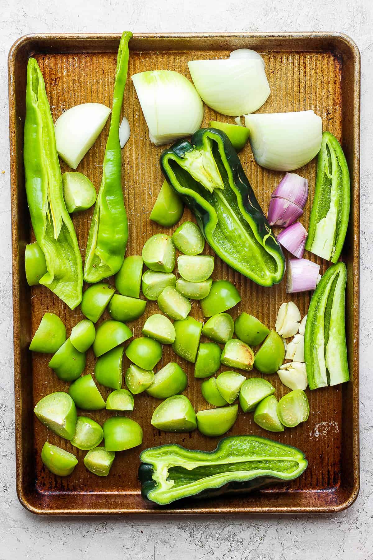The roasted ingredients for salsa verde on a baking sheet before being roasted.