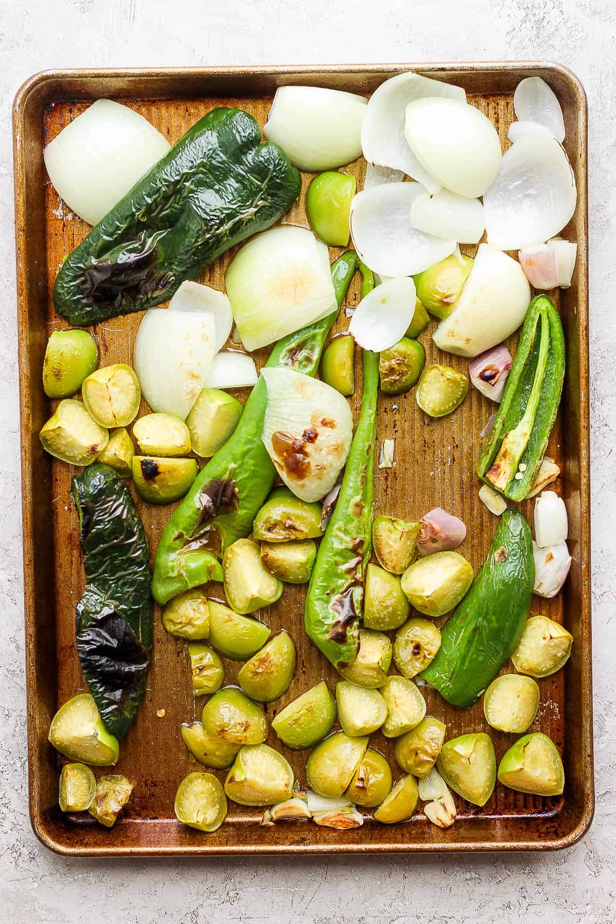 The roasted ingredients for salsa verde on a baking sheet after being roasted.
