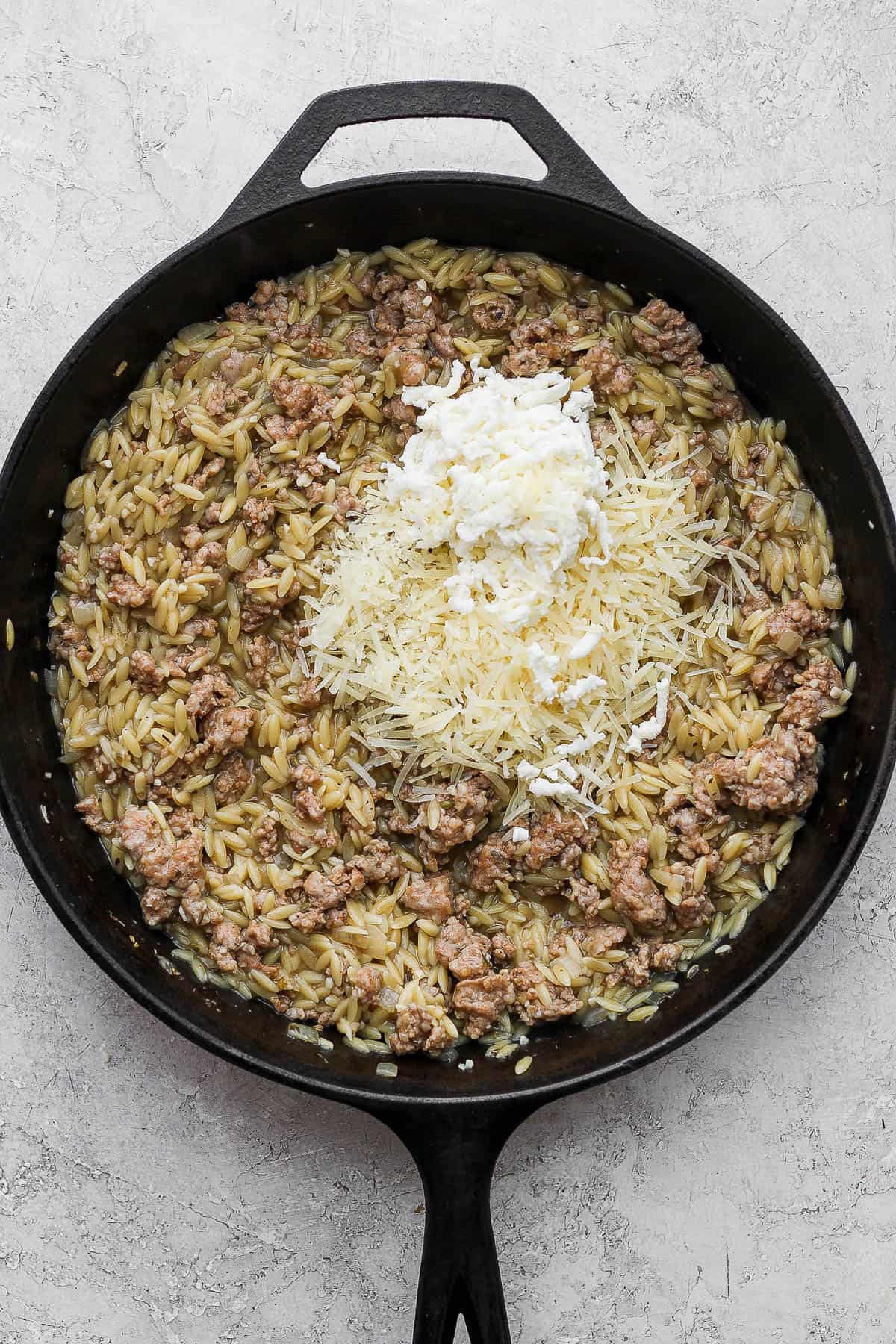The sausage skillet with the orzo fully cooked and cheese added on top.