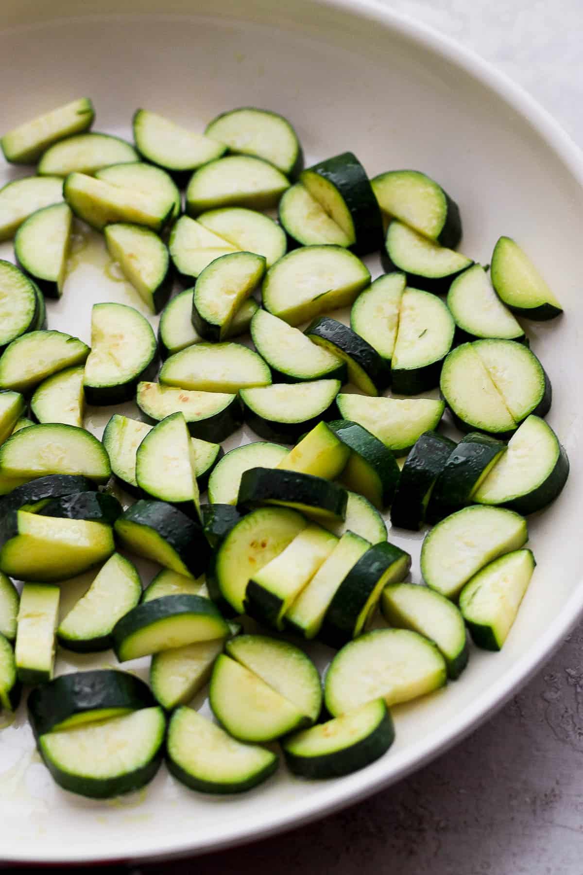 Fresh zucchini sautéing in a separate skillet.