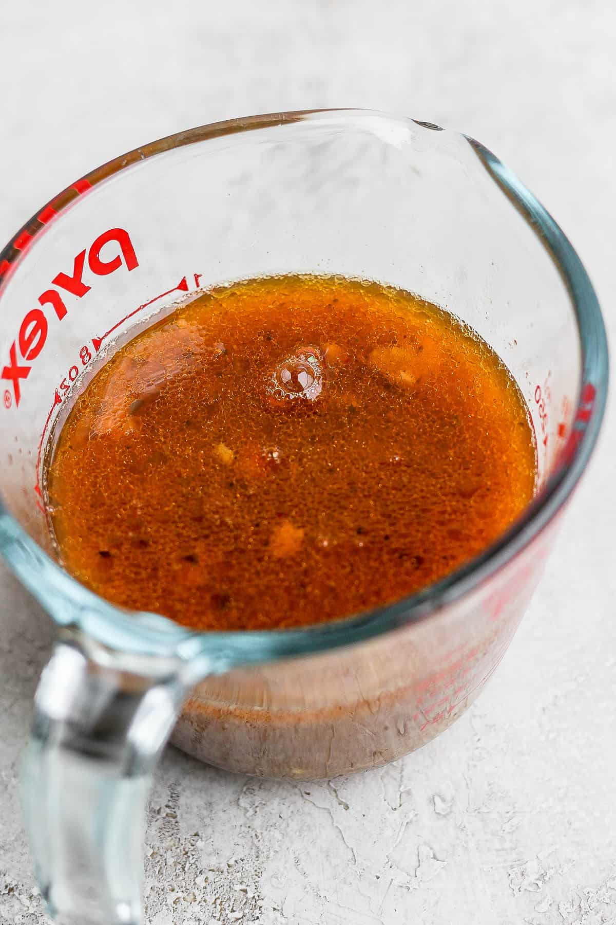 A glass measuring cup with the braising liquid in it.