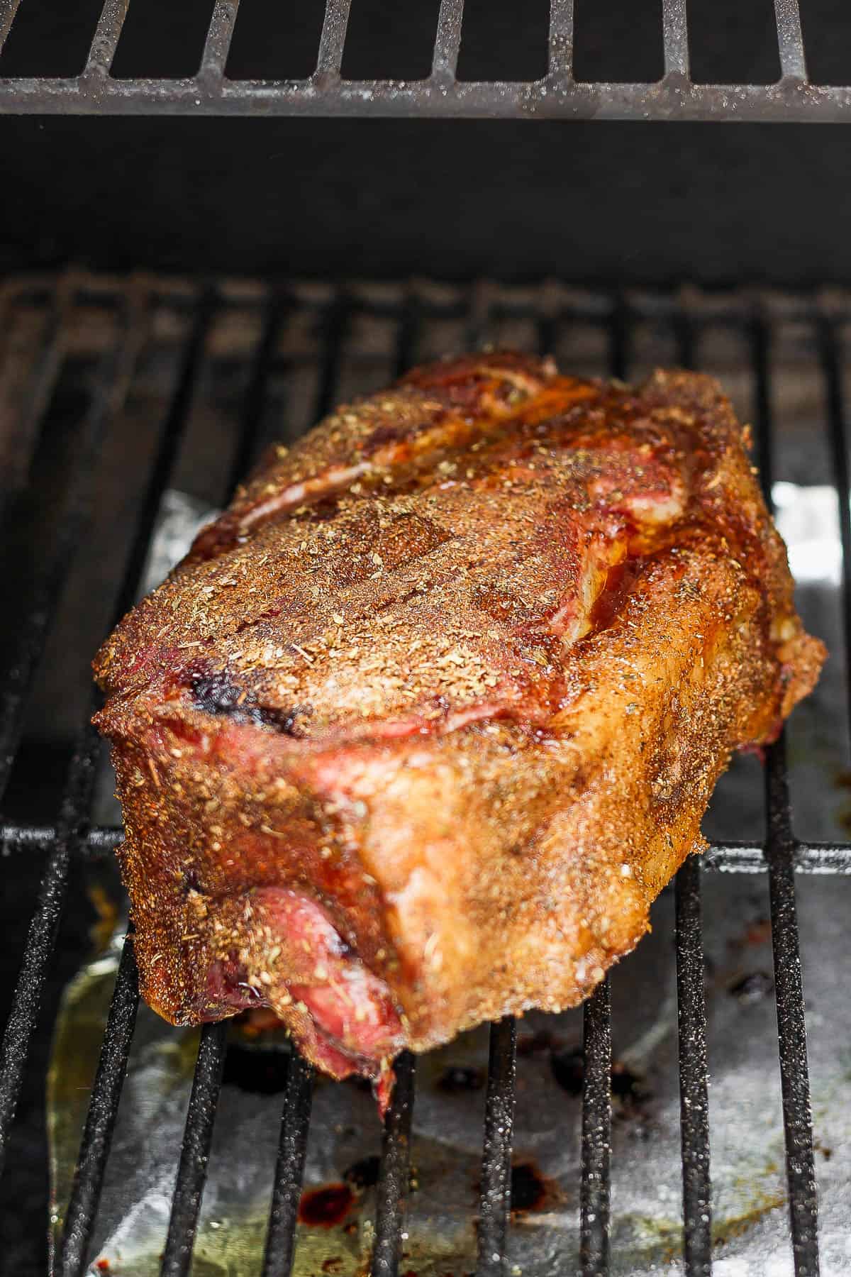 Seasoned pork shoulder on the grates of the smoker.