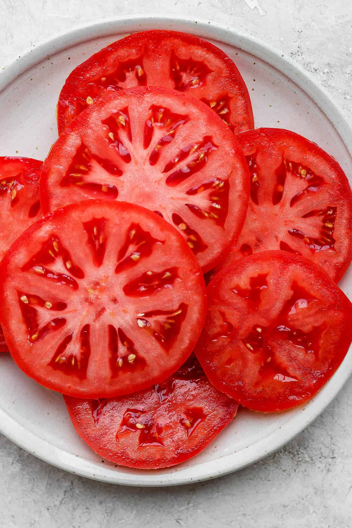 Thick slices of fresh tomato on a plate.