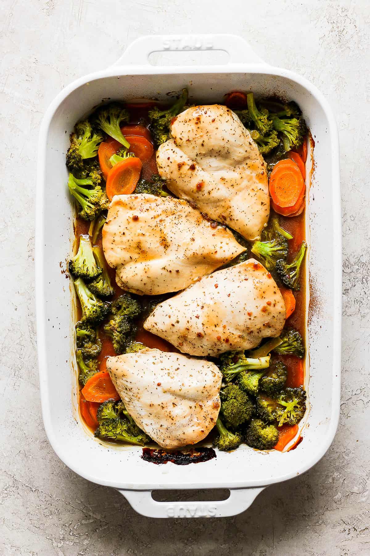 Cooked chicken and veggies in the baking sheet.