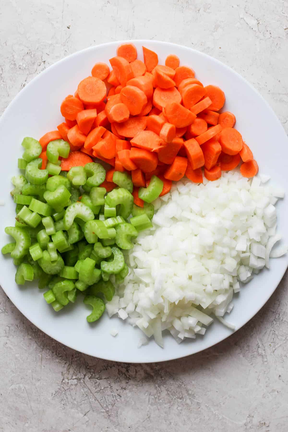 Chopped celery, carrot, and onion on a plate.