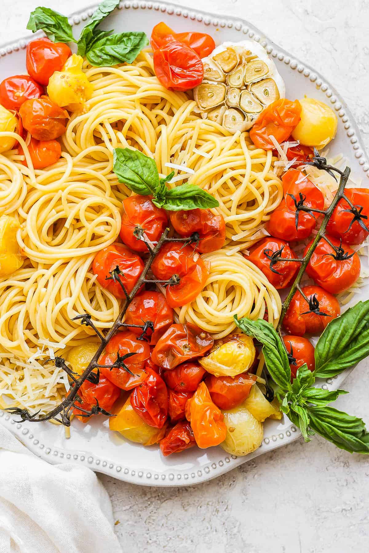 A plate with cherry tomato pasta and fresh basil.