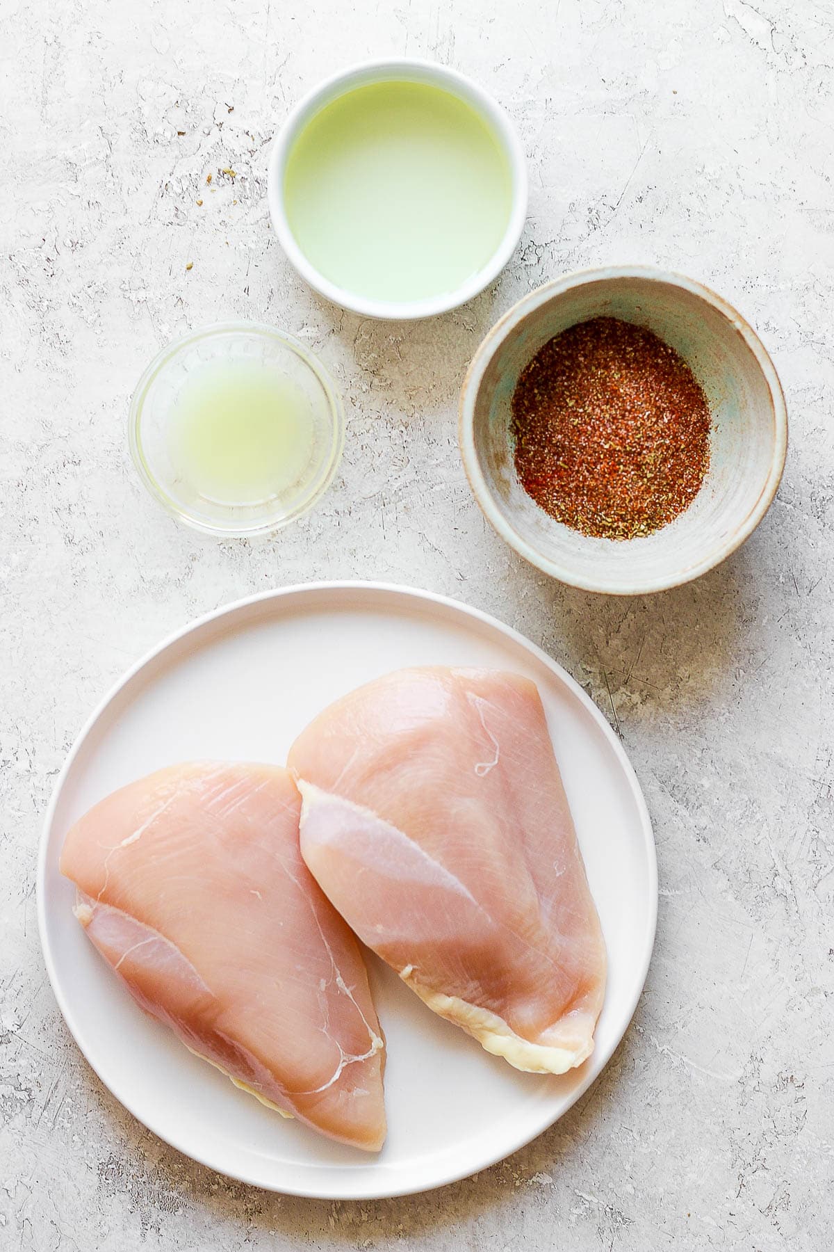 Chicken breasts and chicken fajita marinade ingredients in separate bowls.