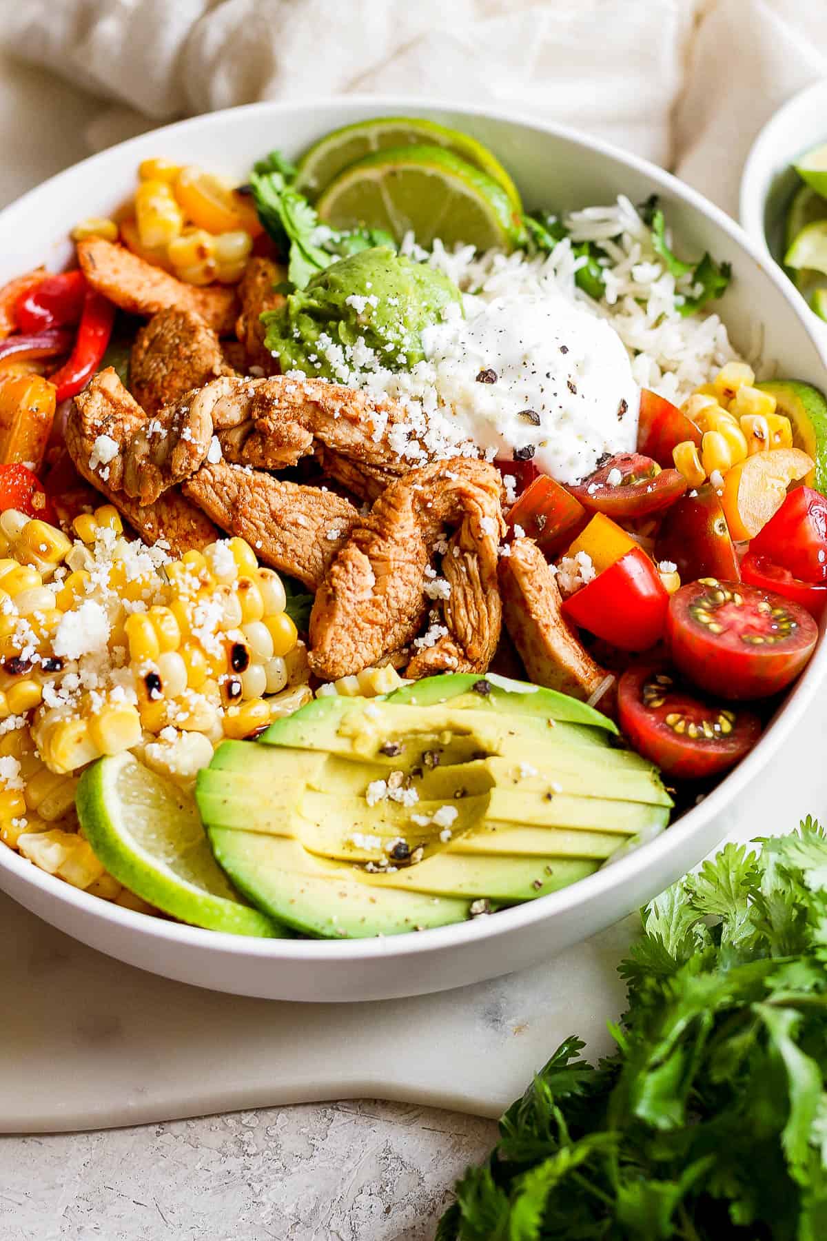 A close-up shot of all the fresh ingredients added on top of the chicken fajita bowl.