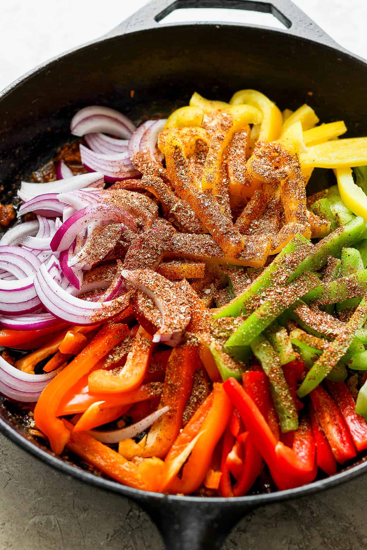 Onion and bell pepper slices in a cast iron skillet with the fajita seasoning.