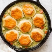 Top down shot of a cast iron skillet filled with chicken pot pie with biscuits.