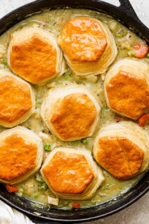 Top down shot of a cast iron skillet filled with chicken pot pie with biscuits.