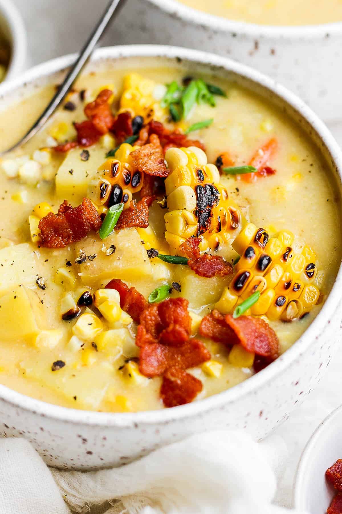 A close-up shot of the corn chowder with toppings.
