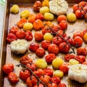 Side shot of a pan of roasted cherry tomatoes and garlic.