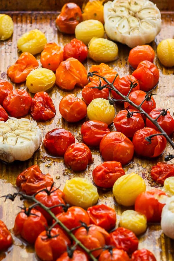 Side shot of a pan of roasted cherry tomatoes and garlic.