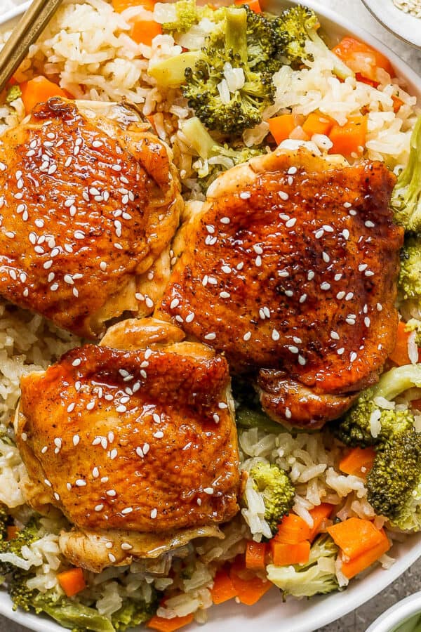 Top down shot of a plate of teriyaki chicken and rice with sesame seed garnish and a fork on the side.