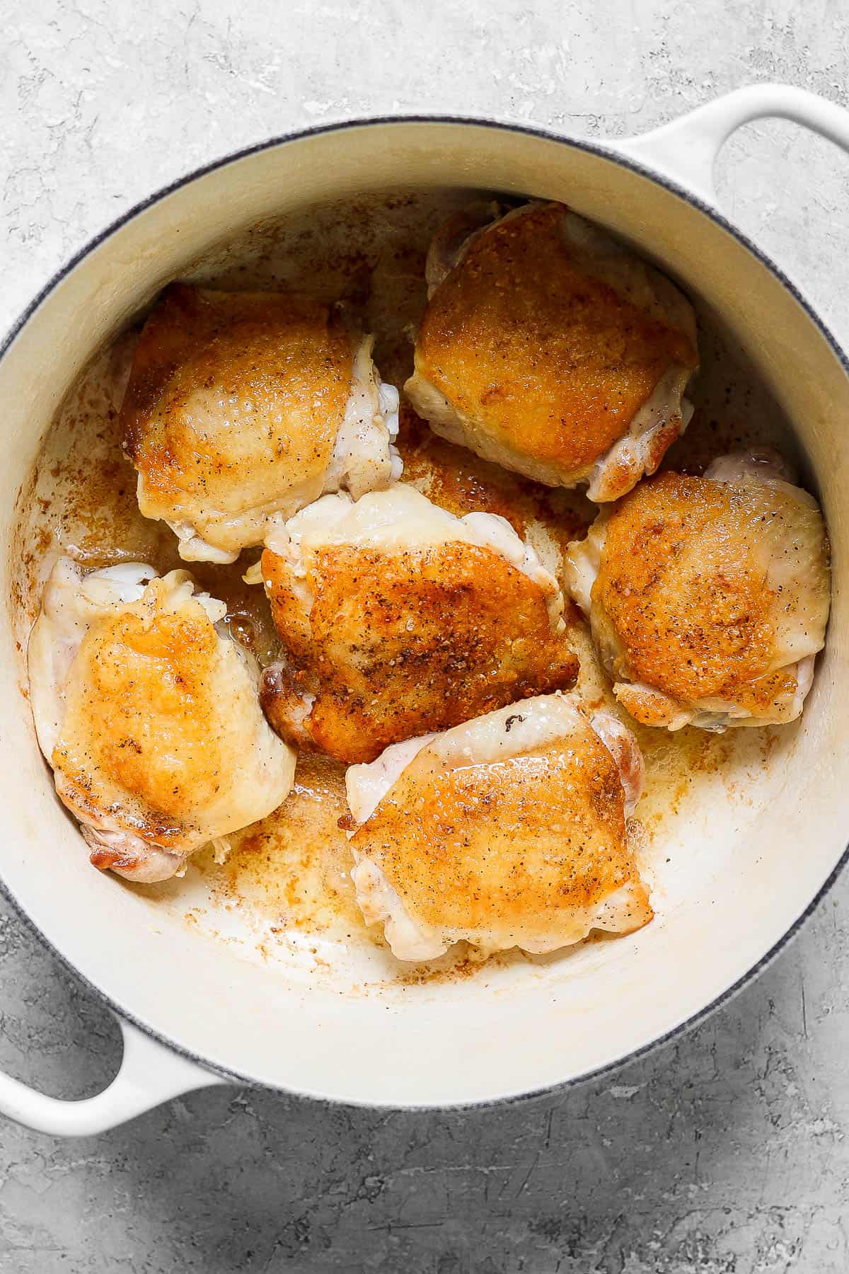Chicken thighs searing in a dutch oven.