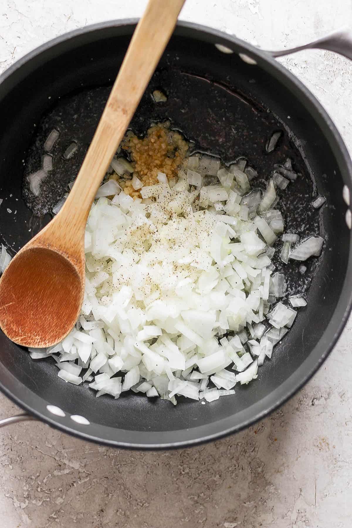 A dutch oven with melted butter, onion, and garlic.