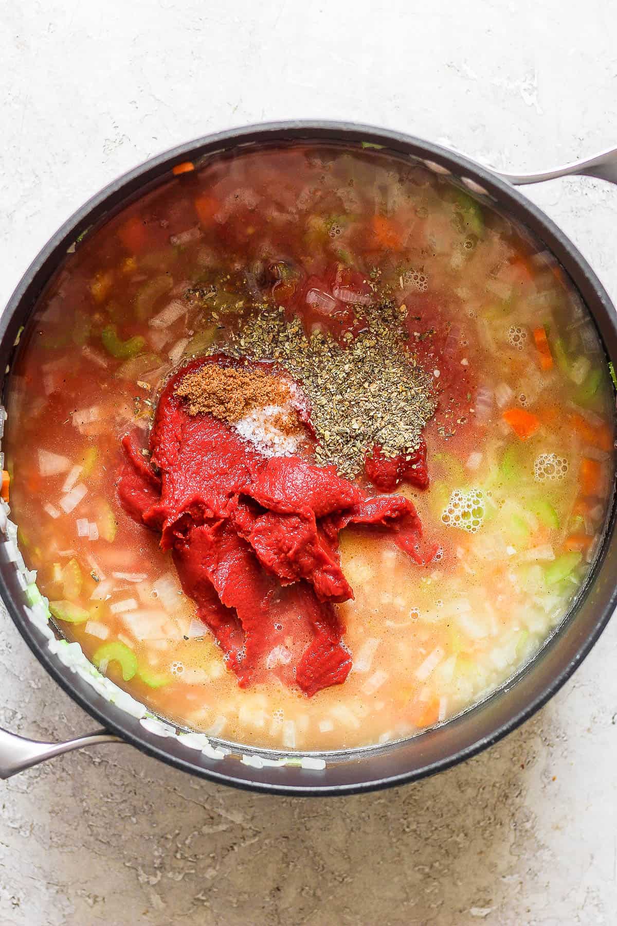 Broth, crushed tomatoes, tomato paste, seasonings, lemon zest, and coconut sugar added to the pot.